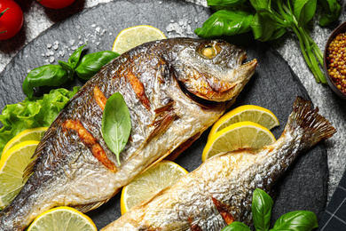 Delicious roasted fish with lemon on slate plate, closeup