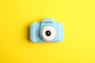 Light blue toy camera on yellow background, top view. Future photographer