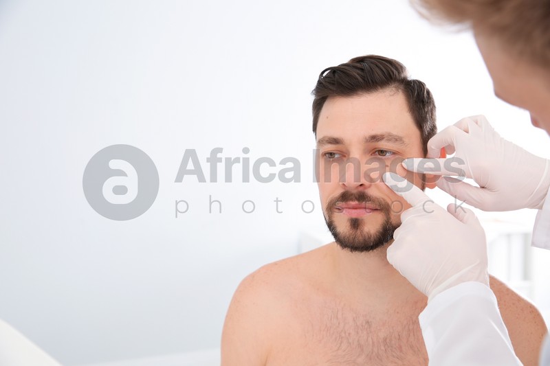 Dermatologist examining patient's birthmark in clinic. Space for text