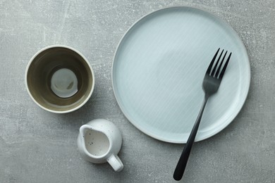 Stylish empty dishware and fork on light grey table, flat lay
