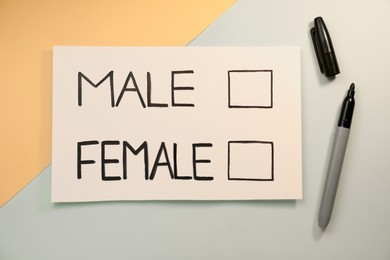 Photo of Marker near card with words Male and Female on color background, flat lay