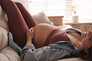 Pregnant young woman with big belly lying on sofa at home