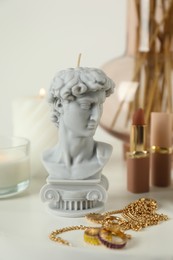 David bust candle and bijouterie on white table. Stylish decor