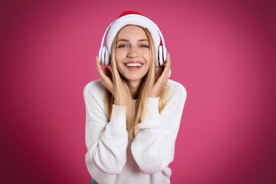 Happy woman with headphones on pink background. Christmas music