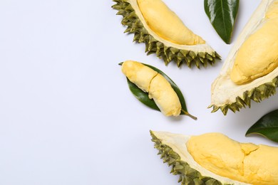 Pieces of fresh ripe durian and leaves on white background, flat lay. Space for text