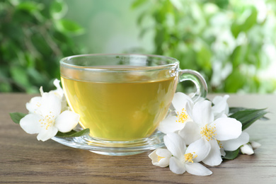 Cup of tea and fresh jasmine flowers on wooden table