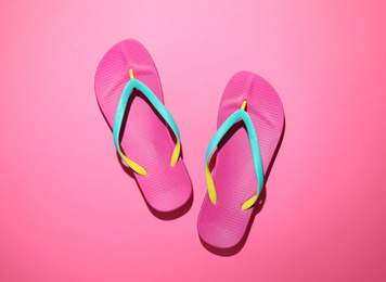 Photo of Pair of stylish flip flops on pink background, top view. Beach objects