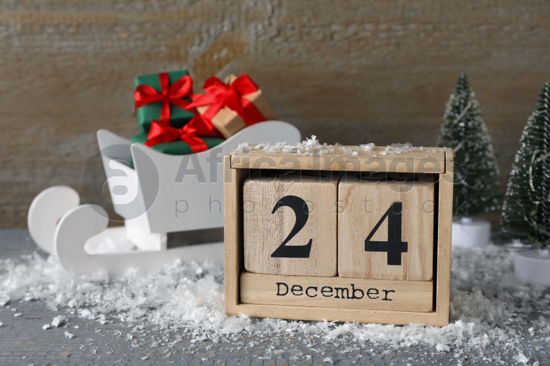 Photo of December 24 - Christmas Eve. Wooden block calendar and decor on grey table