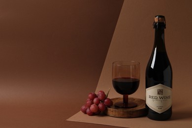 Delicious red wine and grapes on brown background, space for text