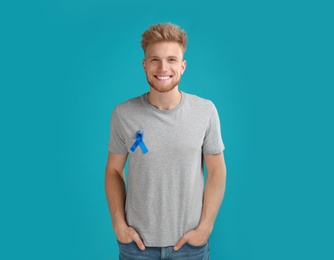 Photo of Young man with blue ribbon on turquoise background. Urology cancer awareness