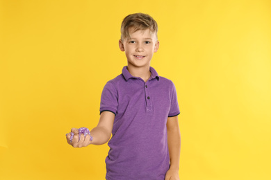 Preteen boy with slime on yellow background