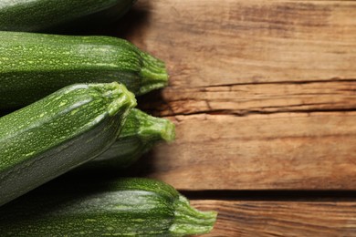 Raw ripe zucchinis on wooden table, closeup. Space for text