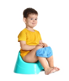 Portrait of little boy sitting on potty against white background