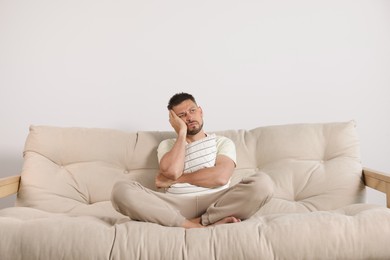 Sleepless man hugging pillow on sofa at home