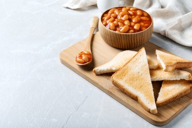 Toasts and delicious canned beans on white table, space for text