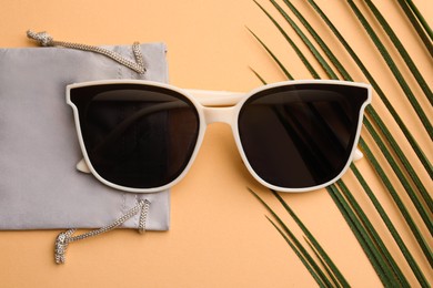 Stylish sunglasses with bag on beige background, top view