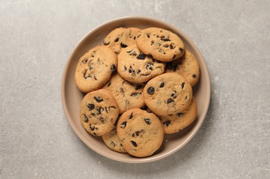 Plate with delicious chocolate chip cookies on grey table, top view