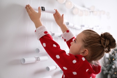 Little girl taking gift from Christmas advent calendar at home