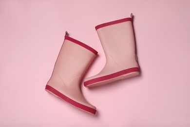 Pink rubber boots on color background, flat lay
