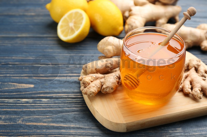 Photo of Ginger and jar of honey on blue wooden table, space for text. Natural cold remedies