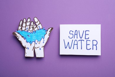 Photo of Save water concept. Hands with water paper figure near card on violet background, top view