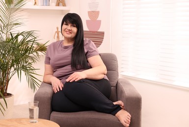 Beautiful overweight woman sitting in armchair at home