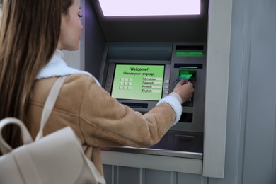 Image of Young woman using cash machine for money withdrawal outdoors