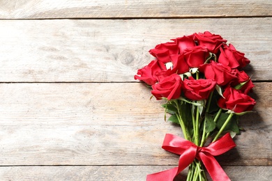 Beautiful red rose flowers on wooden background, top view