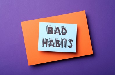 Paper note with words Bad Habits on purple background, top view