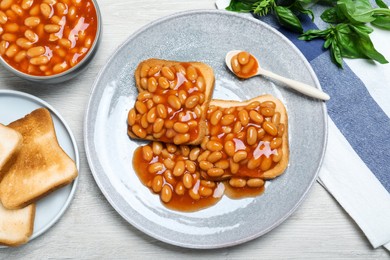 Toasts with delicious canned beans on white wooden table, flat lay