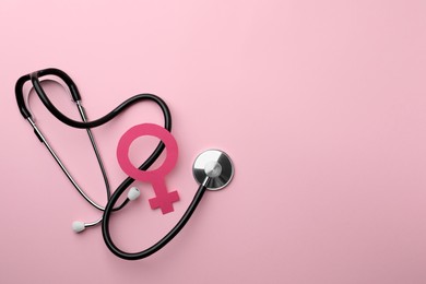 Photo of Female gender sign and stethoscope on pink background, flat lay. Space for text