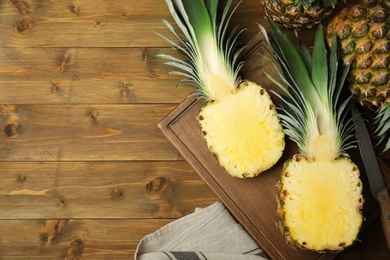Photo of Whole and cut pineapples on wooden table, flat lay. Space for text