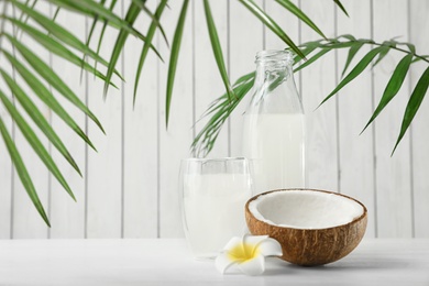 Composition with bottle and glass of coconut water on white wooden table