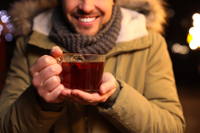 Happy man with mulled wine at winter fair, closeup