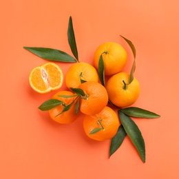 Fresh tangerines with green leaves on coral background, flat lay