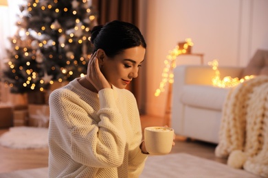 Photo of Young woman with cup of hot drink at home. Christmas celebration