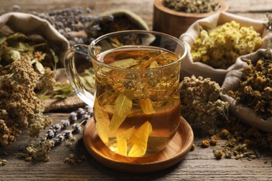 Photo of Freshly brewed tea and dried herbs on wooden table
