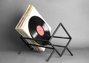 Rack with vinyl records in sleeves on grey background