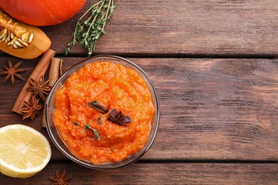 Bowl of delicious pumpkin jam and ingredients on wooden table, flat lay. Space for text