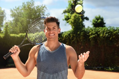 Happy man with tennis racket and ball on court
