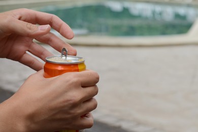 Woman opening tasty canned beverage outdoors, closeup. Space for text