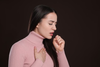 Young woman coughing on dark background. Cold symptoms