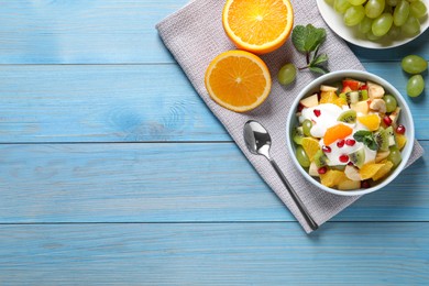 Delicious fruit salad served on light blue wooden table, flat lay. Space for text