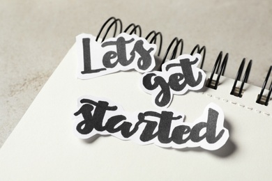 Sheets of paper with phrase Let's Get Started and notebook on grey table, closeup
