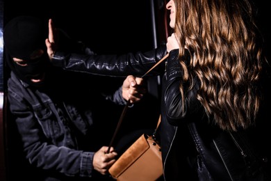 Woman fighting with thief while he trying to steal her bag outdoors at night, closeup. Self defense concept