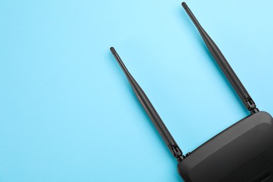 Modern Wi-Fi router on light blue background, top view. Space for text
