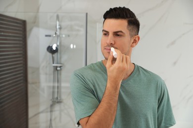 Man applying hygienic lip balm in bathroom