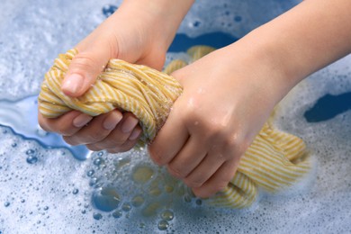 Photo of Woman wringing garment over basin, closeup. Hand washing laundry