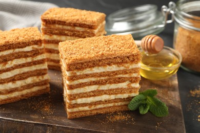 Delicious layered honey cake on wooden board, closeup