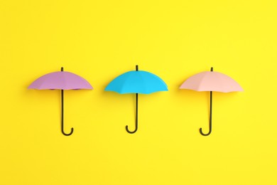 Bright toy umbrellas on yellow background, flat lay